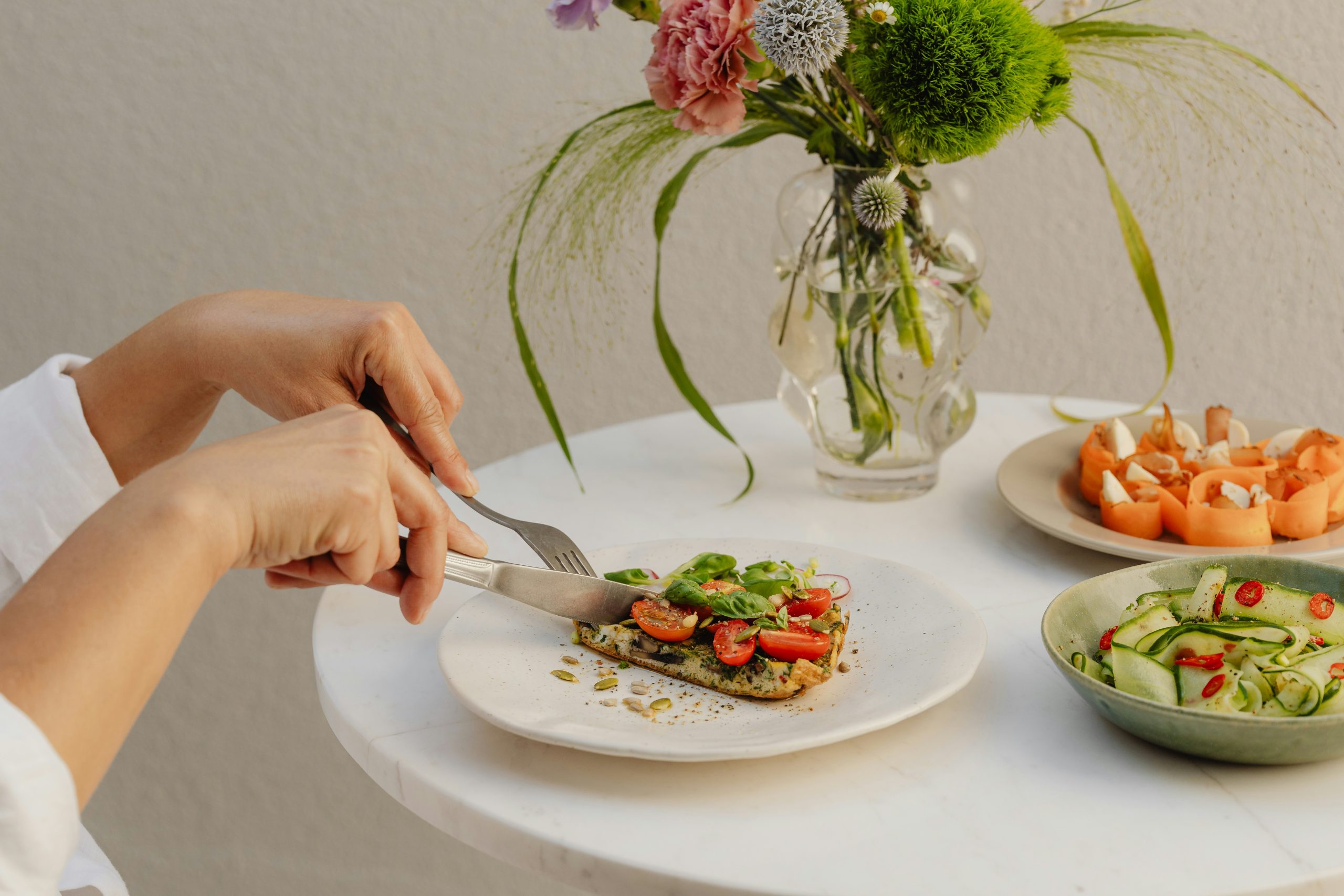 migren-fejfajas-okai-melegfront | Marie Claire Szépen terített asztal, fiatal nő reggelit vág