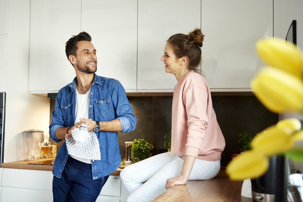 Egy pár mosolyogva beszélget a konyhában
