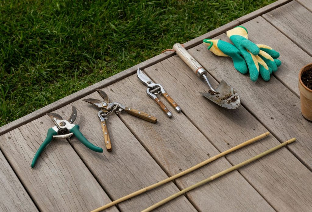 marciusi-kerti-munkak-szerszamok | Marie Claire Márciusi kerti munkákhoz szükséges eszközök fa felületen: metszőollók, ásó, kesztyű