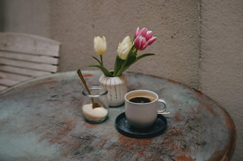 Reggeli kávé az asztalon egy tulipáncsokor mellett