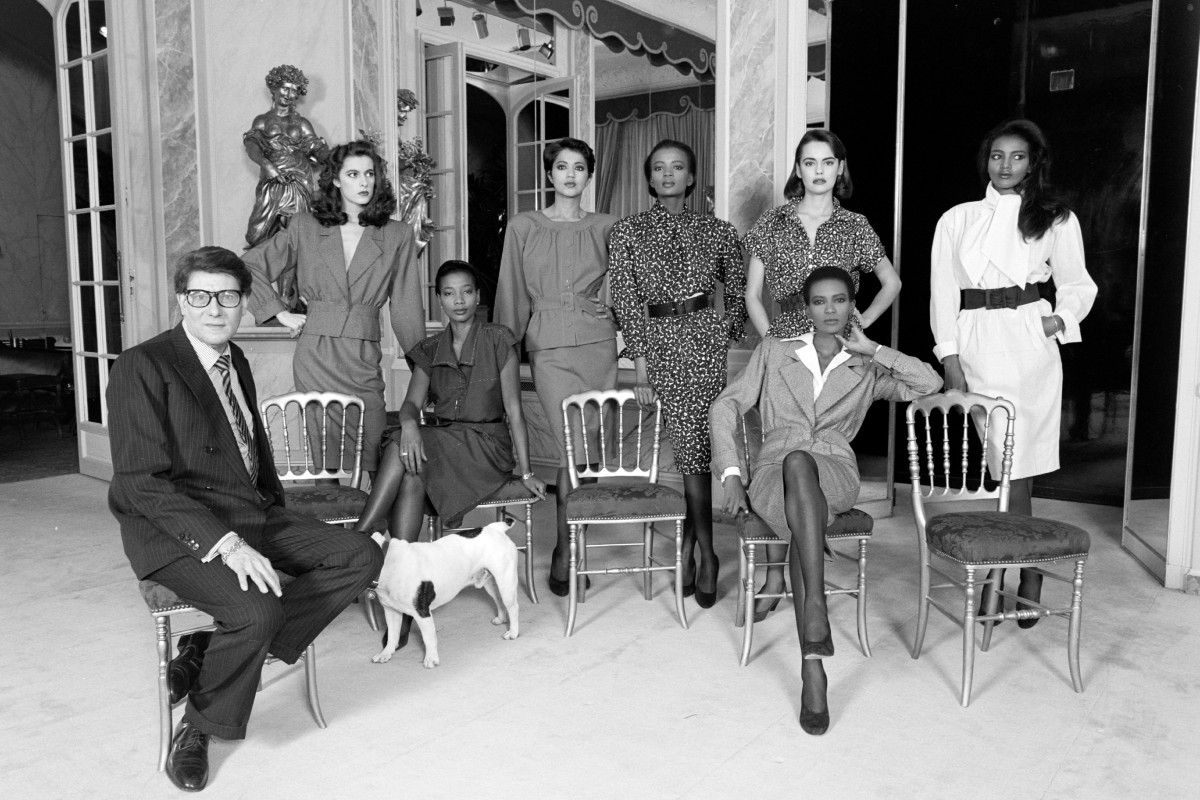 Yves Saint Laurent a bemutatótermében ül Mounia Orosemane, Kirat Young (más néven Kirat Bhinder), Rebecca Ayoko, Leslie Branner, Amalia Vairelli és Khadija Adams modellekkel, akik mind az 1986-os tavaszi Couture kollekció darabjait viselik