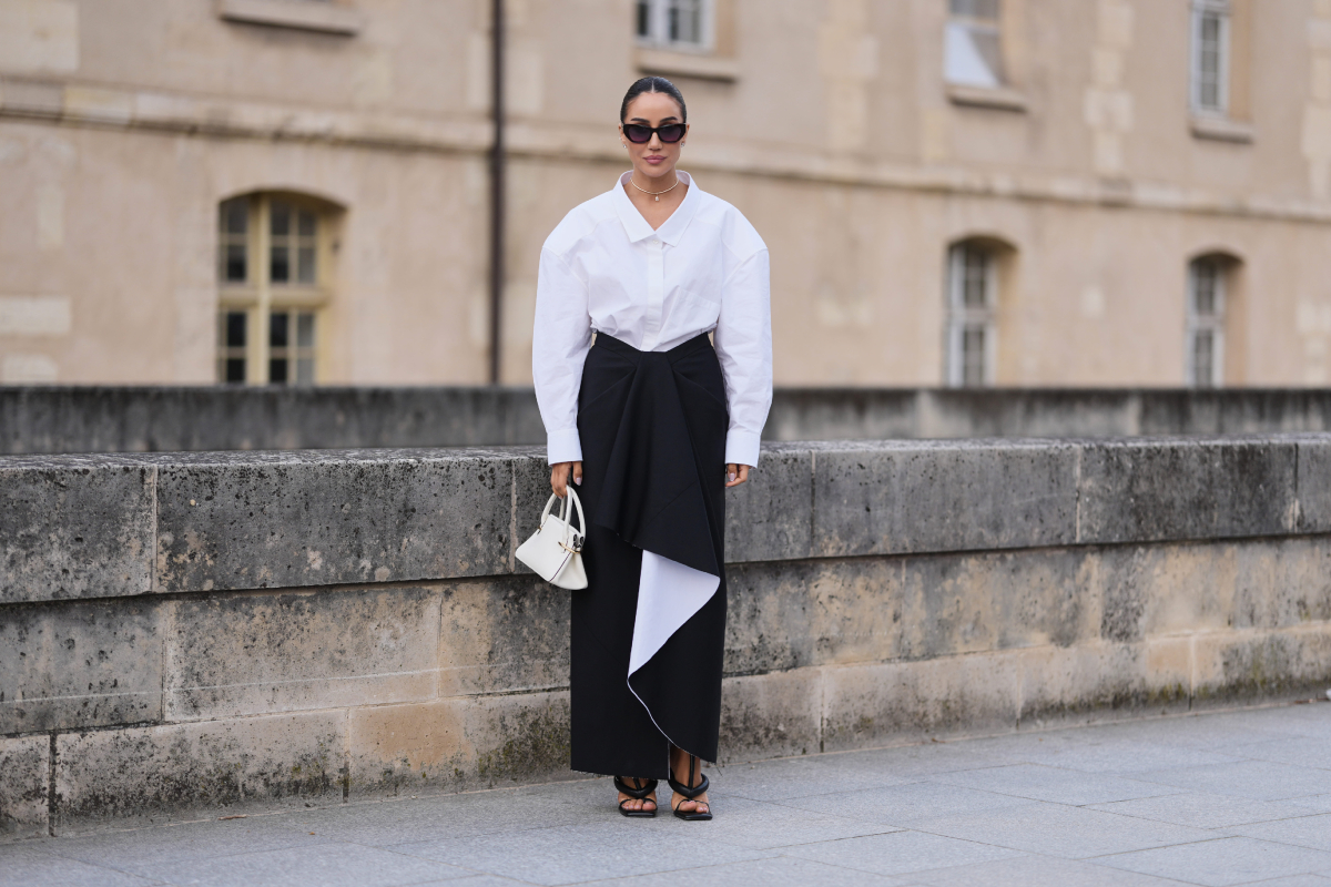 Tamara Kalinic kontyba fogott hajjal és fekete napszemüvegben látható; egy hófehér, túlméretezett pamutinget visel, amelyet egy fekete, aszimmetrikus drapériával díszített, fehér bélésű midi szoknyával kombinált. Megjelenését fehér bőrtáskával és fekete, pántos bőr magas sarkú szandállal tette teljessé a Givenchy bemutatója előtt a párizsi divathéten