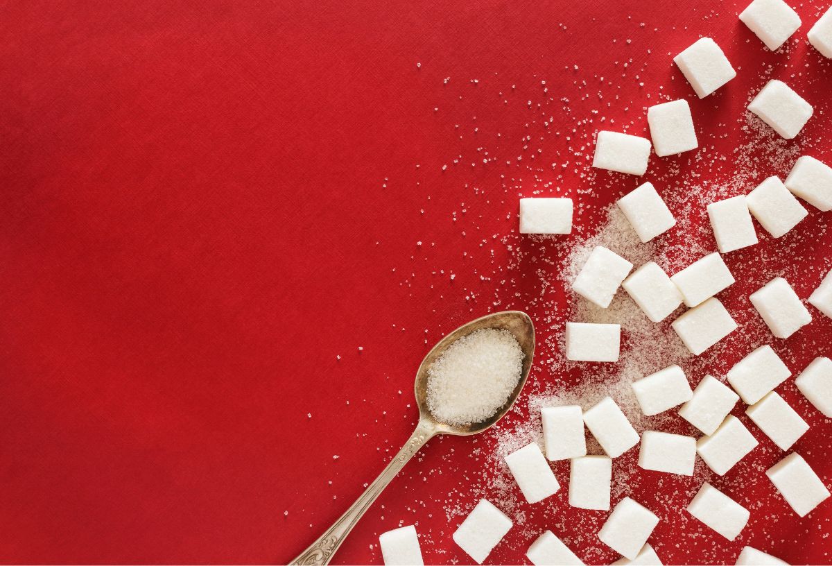 piros háttéren kockacukrok, kiskanálban szukralóz mesterséges édesítő