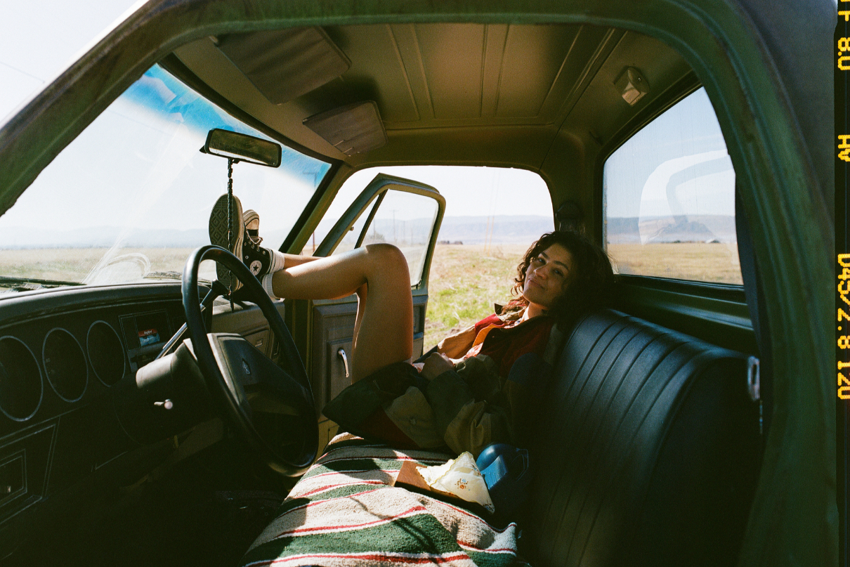 Zendaya egy autó anyósülésén, feltett lábbal