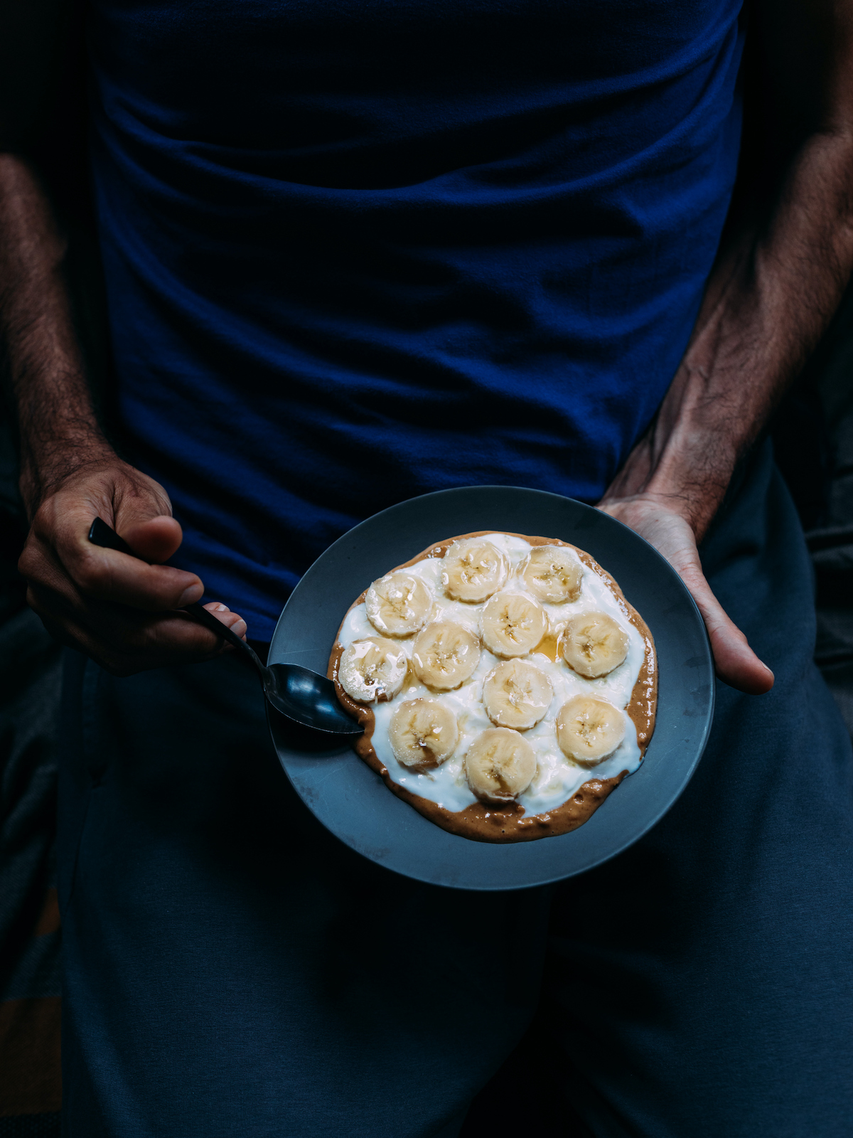 férfi ölében banánnal díszített palacsintát tart, kanállal nyúl hozzá