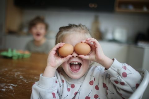 Nevető kislány tojásokat tart a szeme előtt