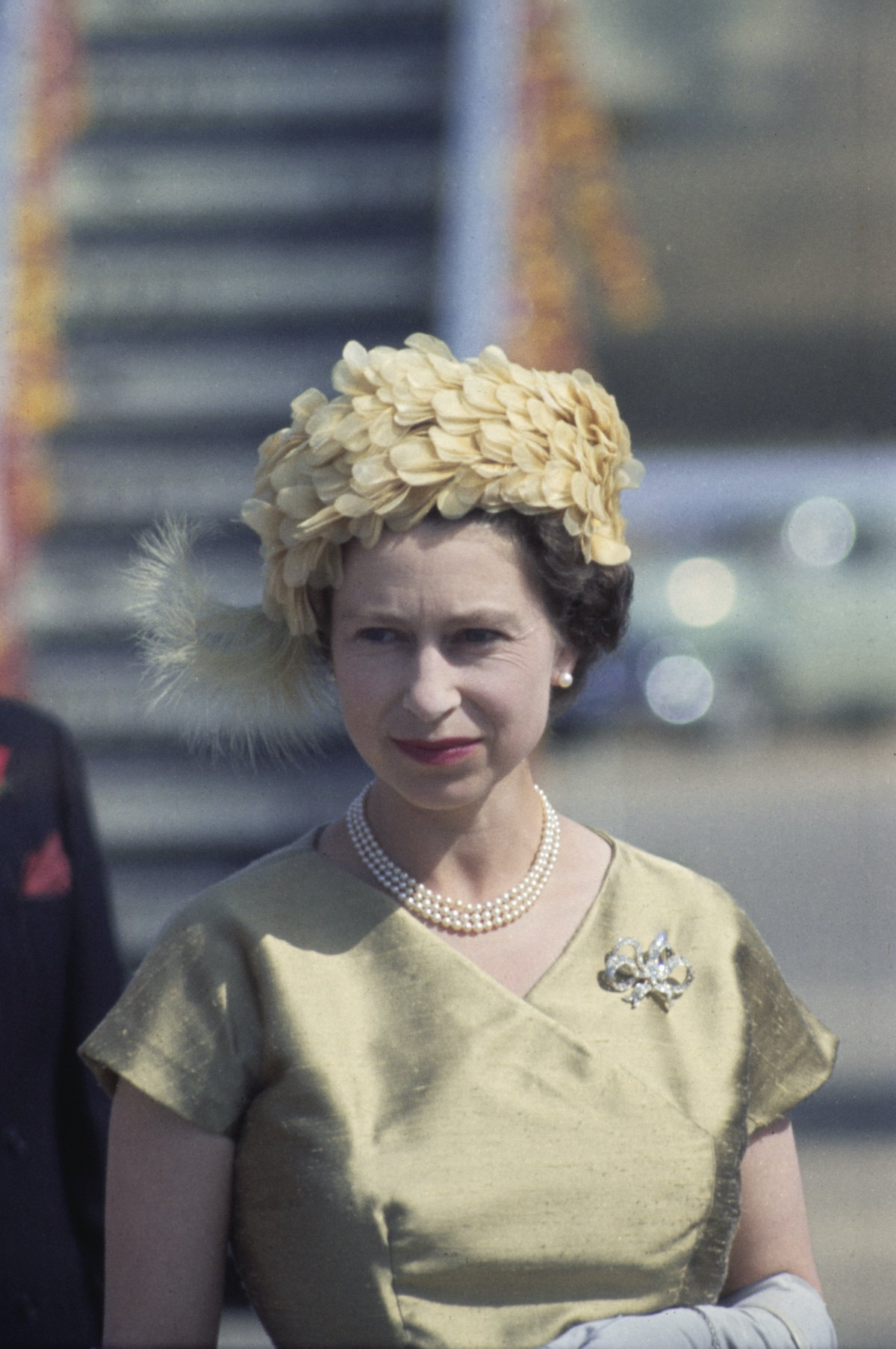 Erzsébet királynő sárga kalapban és ruhában, nyakán gyöngyökkel