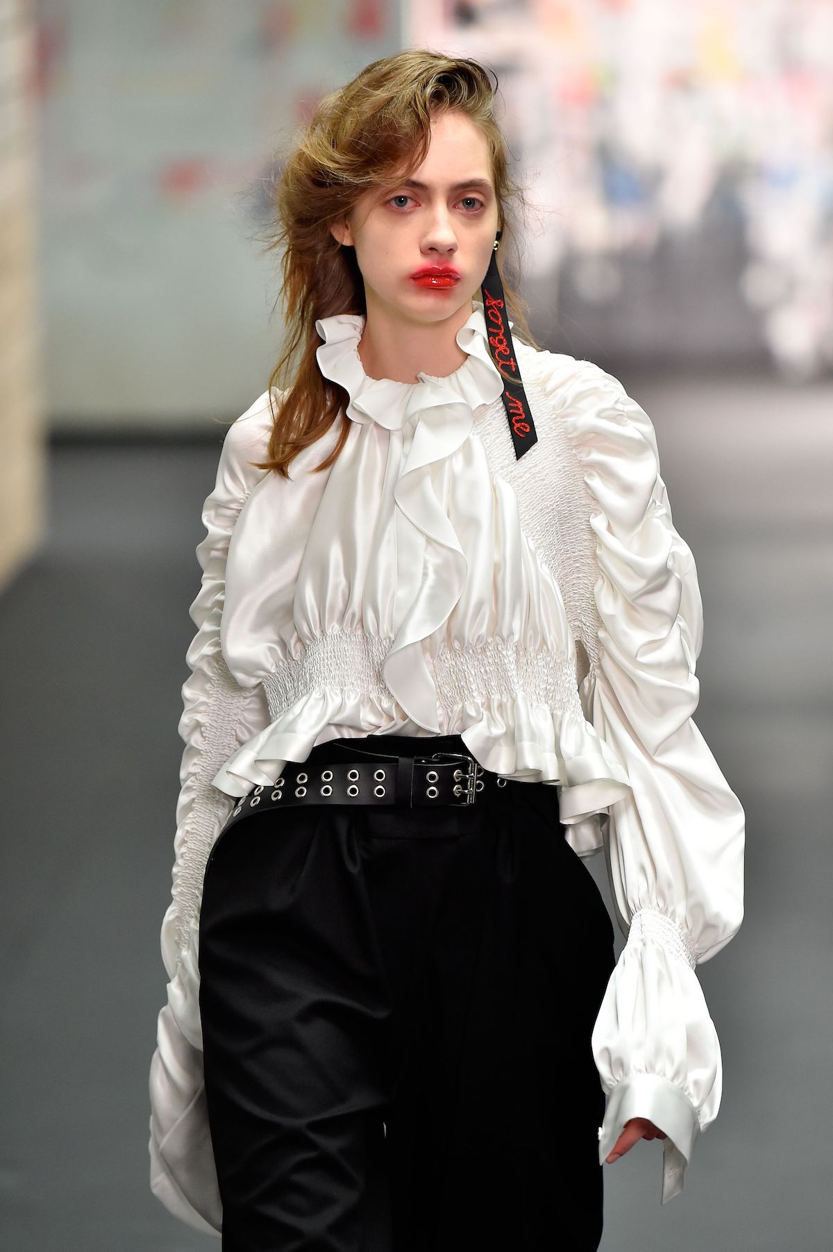 modell a kifutón fehér blúzban, fekete szoknyában, elmosott ajkakkal