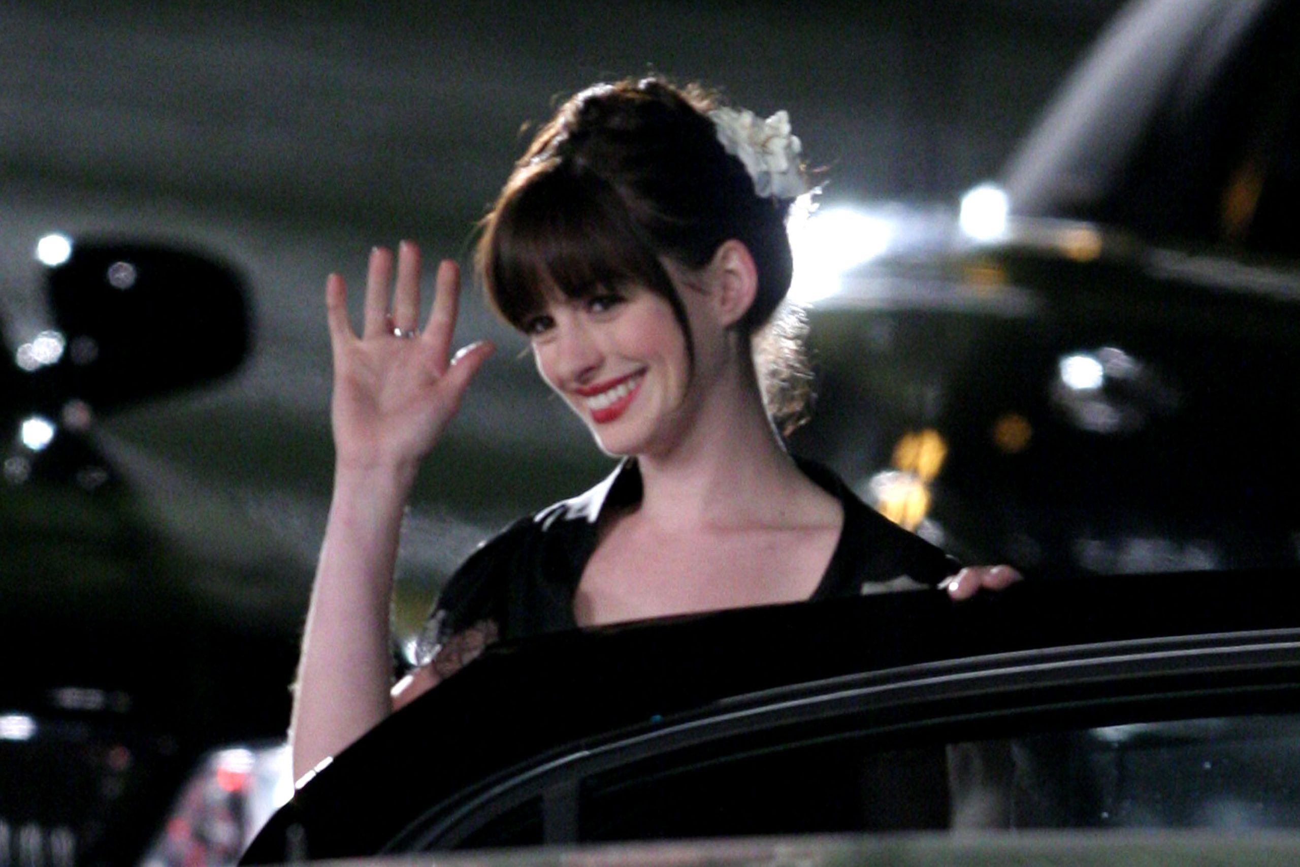 Anne Hathaway frufruval, kocsiból kiszállva integet