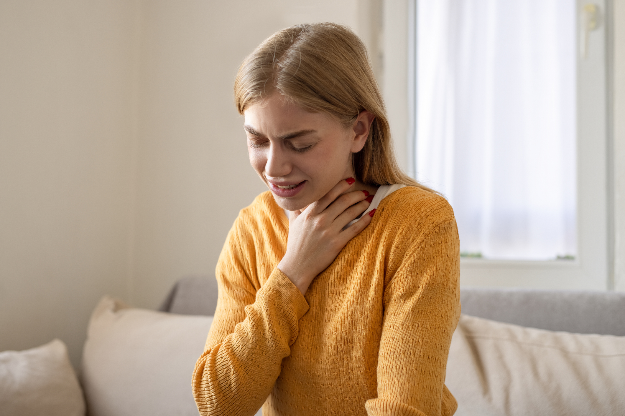 Pajzsmirigy problémákkal küzdő fiatal nő a nyakához kap