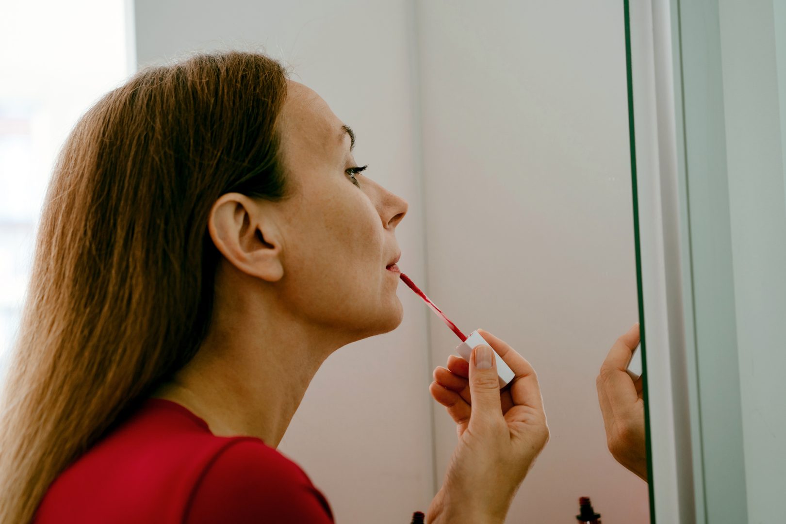 Középkorú nő készülődik, rúzst ken fel.