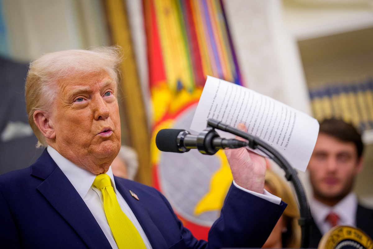 donald-trump-betegsege-orokolt-demencia | Marie Claire Donald Trump sárga nyakkendőben mikrofon előtt iratot tart fel