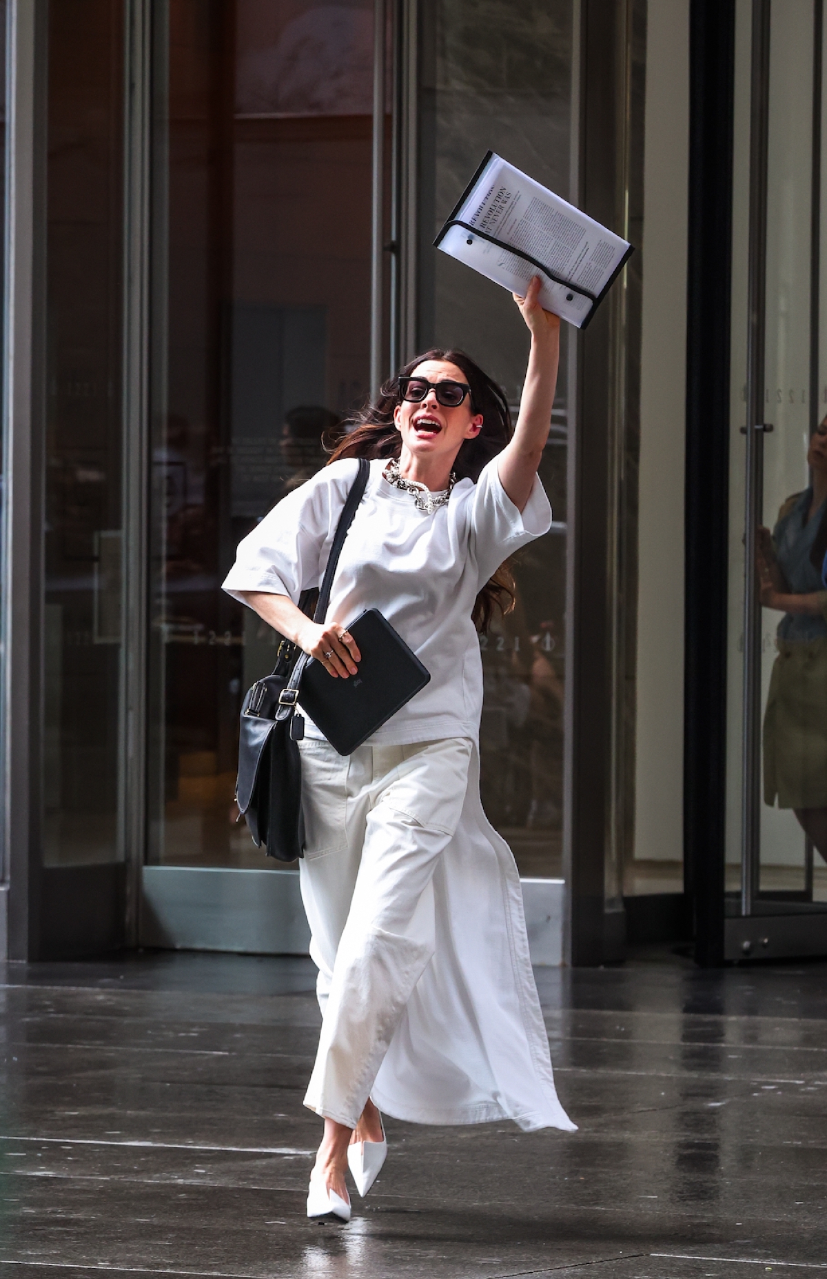 Anne Hathaway mappát a magasba tartva szalad az utcán