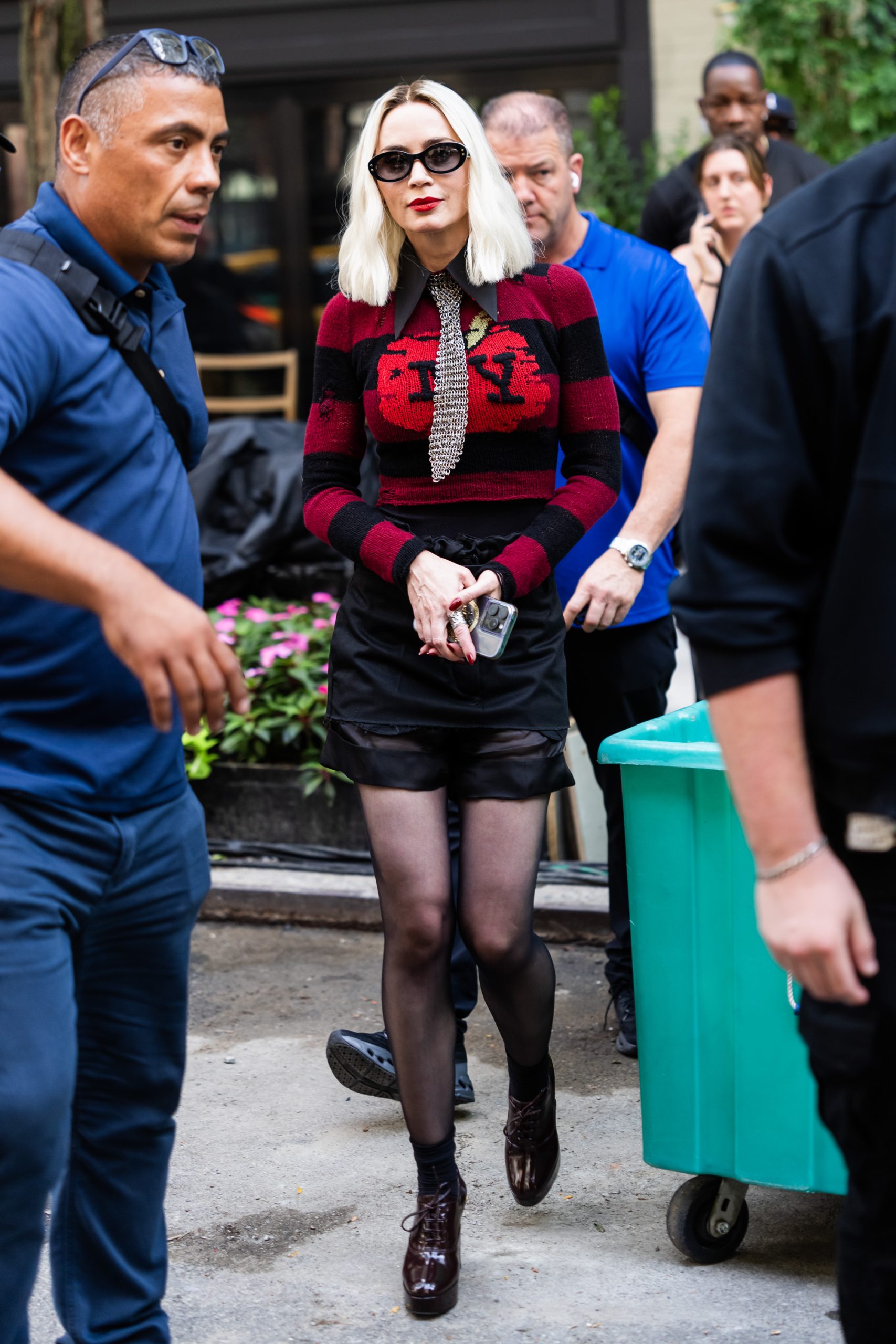 Emily Blunt platinaszőke hajjal és piros fekete blézerben