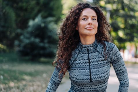 hosszú barna hajú nő erdőben, sportfelsőben