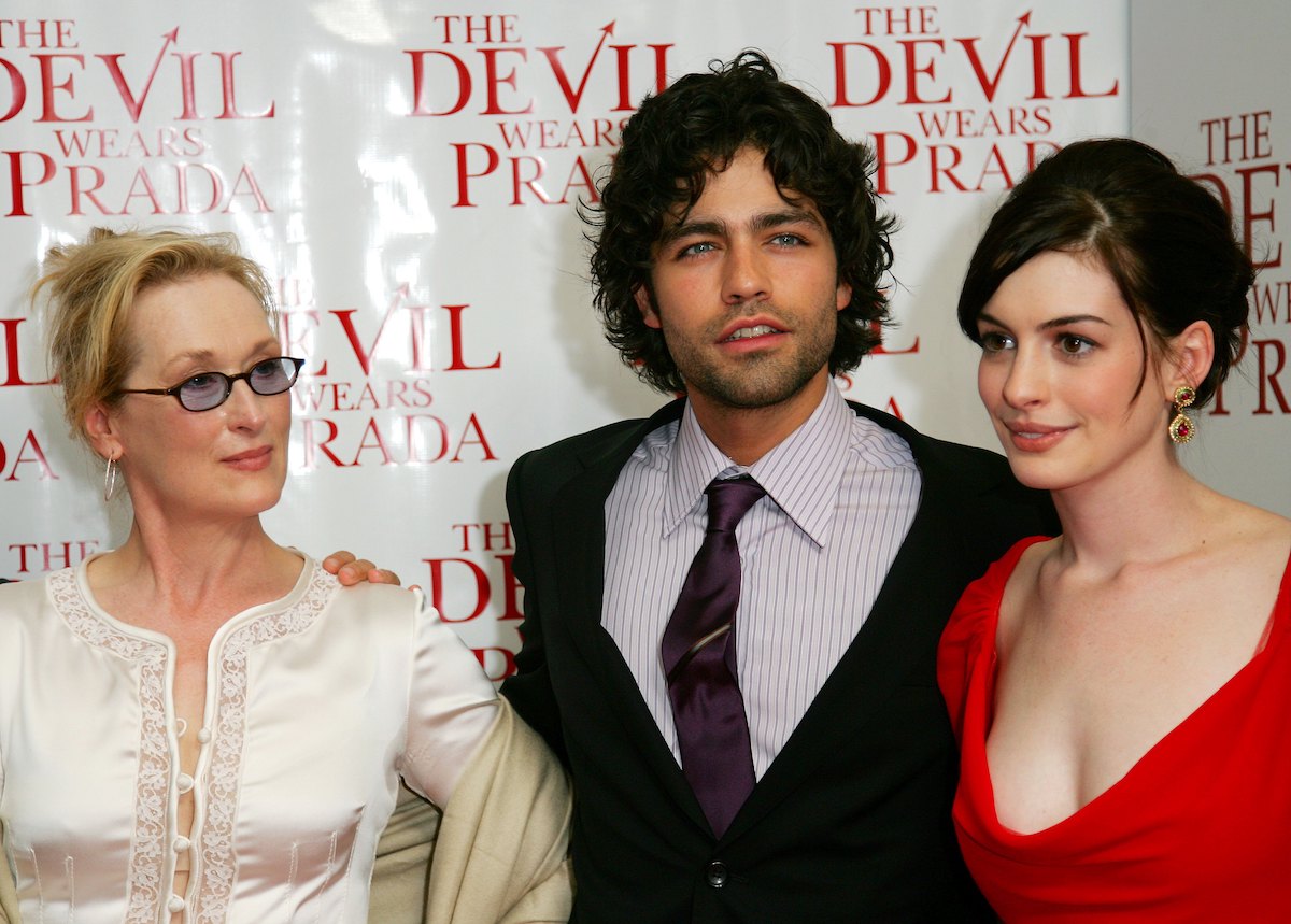 Meryl Streep fehér ruhában és napszemüvegben, mellette Adrian Grenier öltönyben és Anne Hathaway piros ruhában