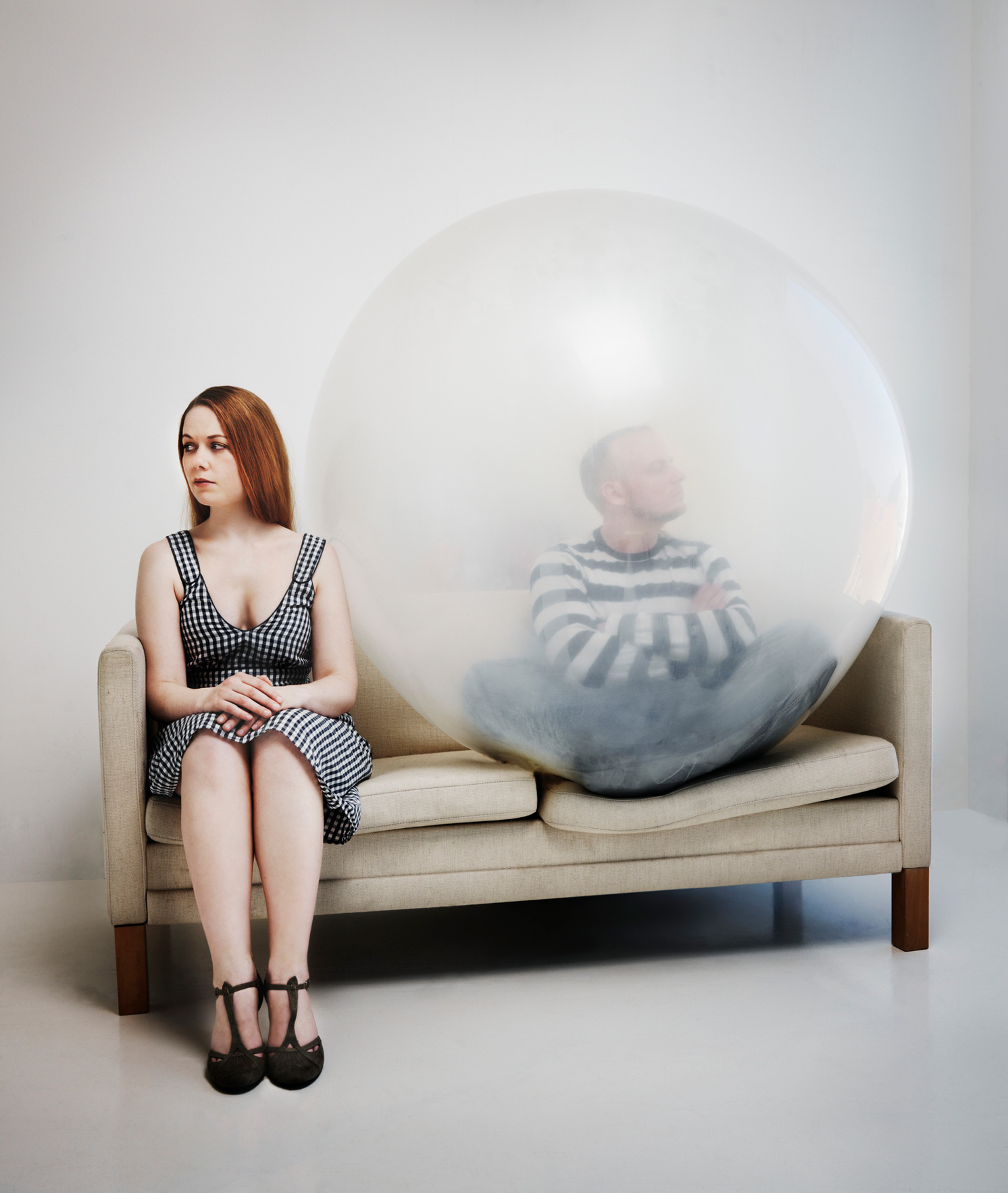 Egy nő és egy férfi ül a kanapén, a nő szomorúan ül és oldalra néz, míg a férfi mérgesen ül egy burokban