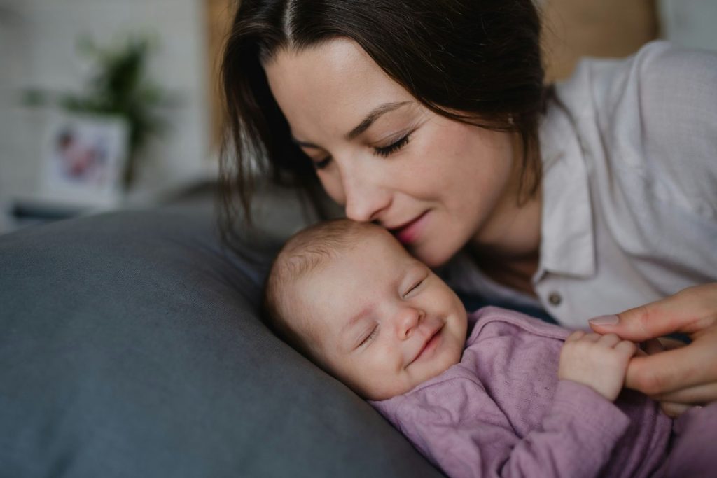 Kisbaba alvás közben nevet, anyukája közel hajol hozzá