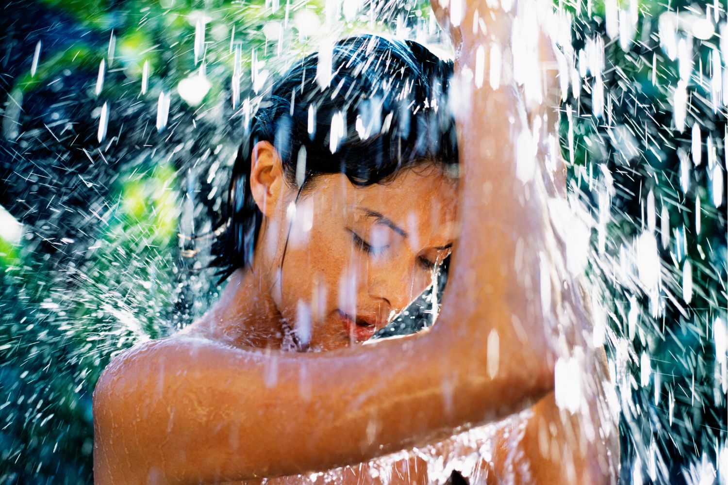 Nő szabadtéren zuhanyzik csukott szemmel