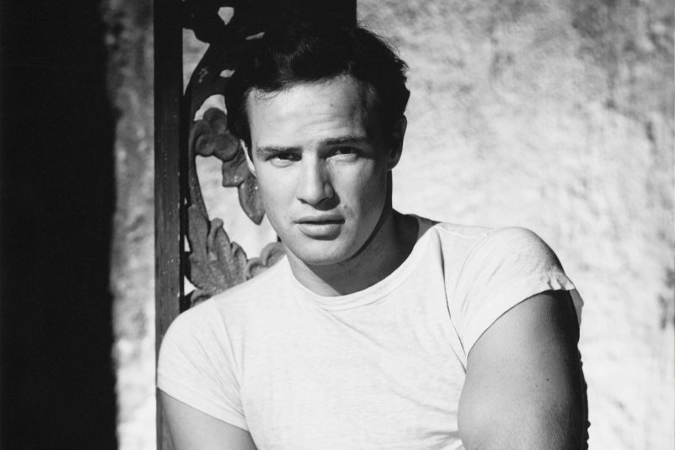 Marlon Brando fehér polóban néz komoly arccal, karjai maga előtt összefonva