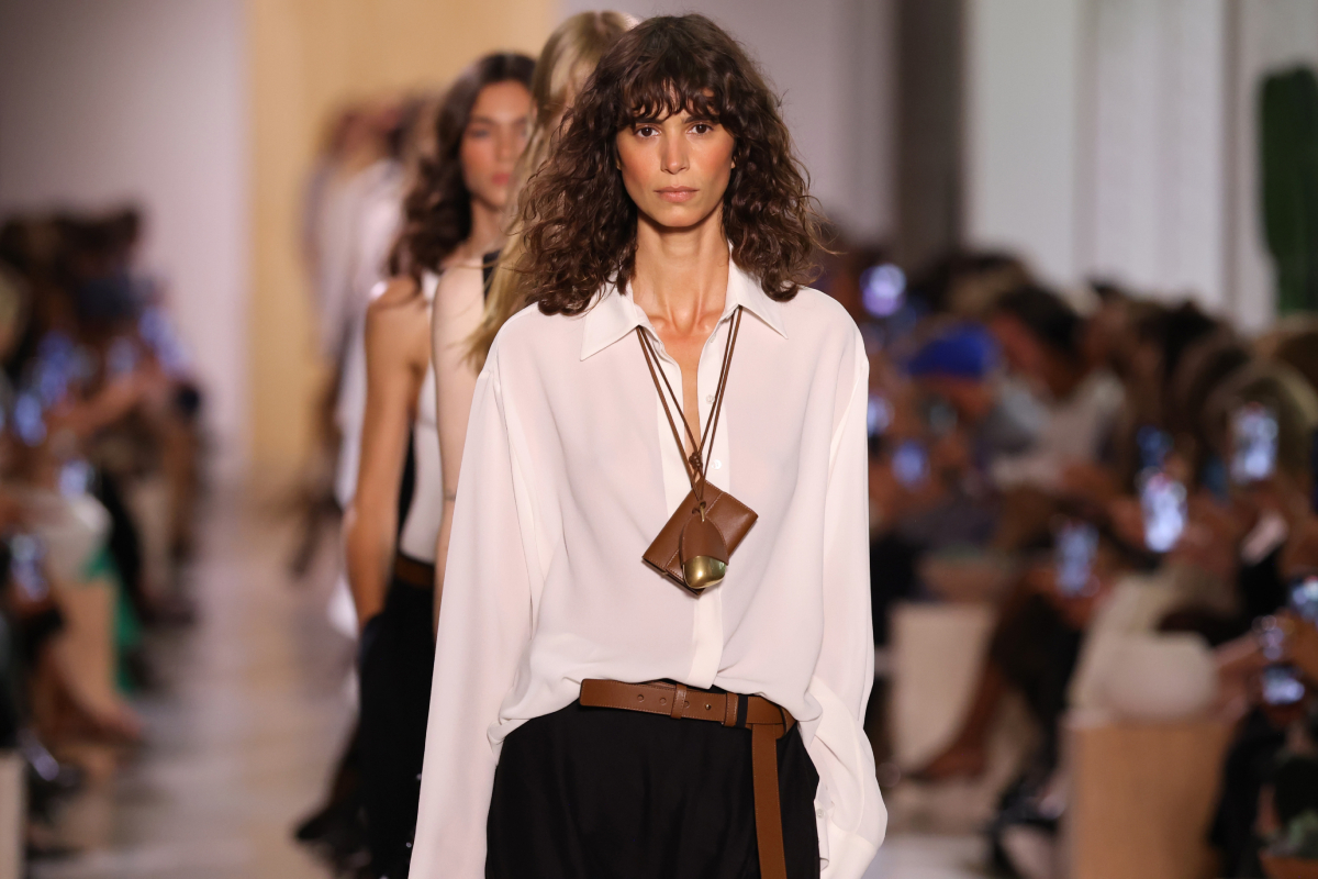 Michael Kors 2026. tavasz–nyár bemutatón barna hajú modell vonul fehér ingben, fekete nadrágban