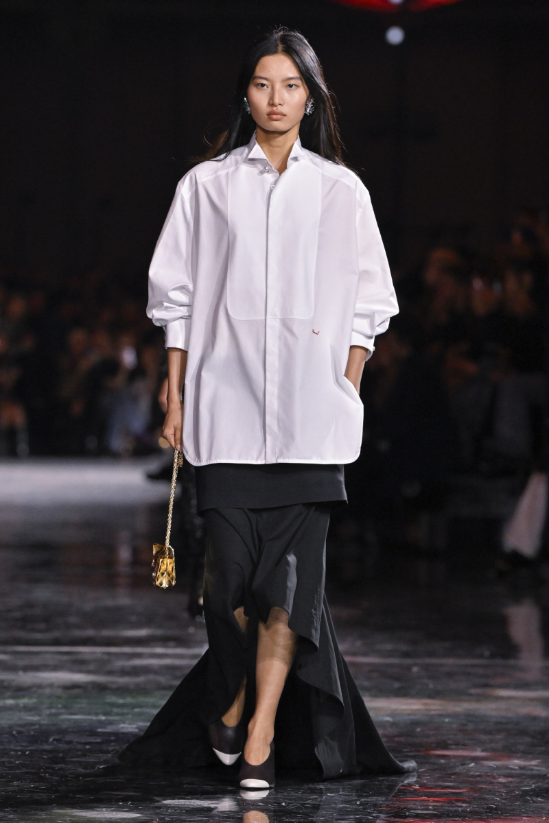 Chanel 2026. tavasz–nyár bemutatón vonuló ázsiai modell fehér bő ingben, fekete szoknyában
