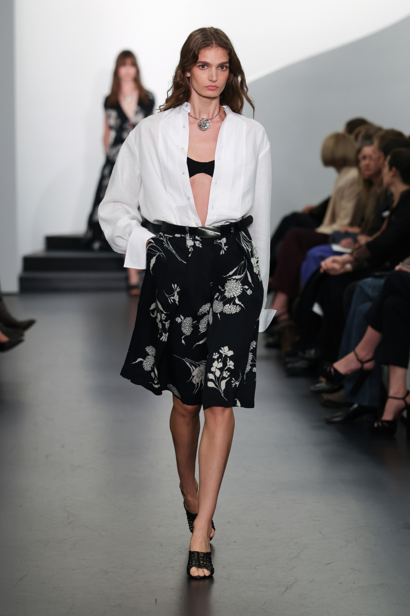 Ralph Lauren 2026. tavasz–nyár bemutatón vonuló modell kigombolt fehér ingben, fekete szoknyában