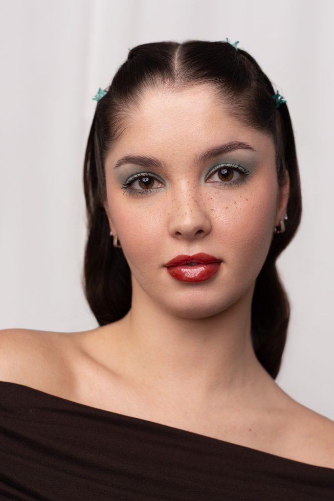 fiatal, sötét hajú nő fehér háttér előtt, glossy lips sminktrend