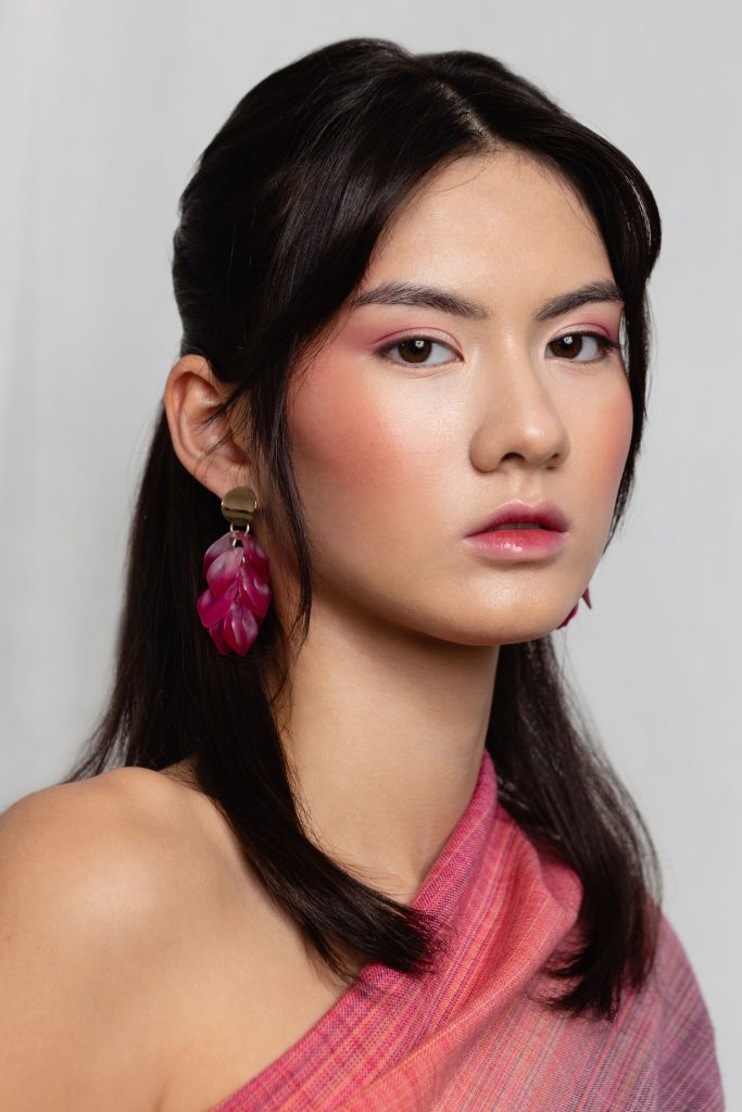 fiatal, sötét hajú nő fehér háttér előtt, glossy lips sminktrend