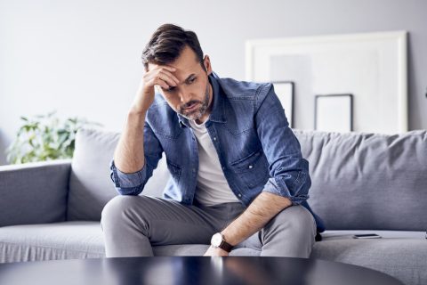 Egy férfi magába roskadva ül a kanapén