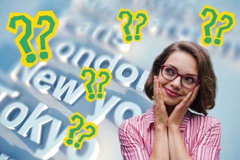 Fővárosok nevei kékes árnyalatú három dimenziós grafikán háttérben, szemüveges, barna hajú nő piros csíkos ingben gondolkodva néz, zöld kérdőjelek