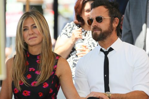 Jennifer Aniston visszafogotton mosolyog, míg Justin Theroux, aki napszemüveget visel, komoly arcot vág