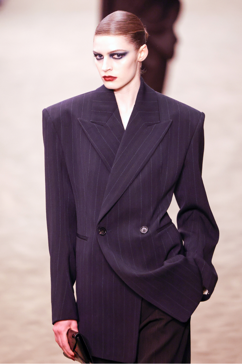 Saint Lauren 2026. ősz–tél bemutatón vonuló modell szoros konttyal, drámai sminkkel