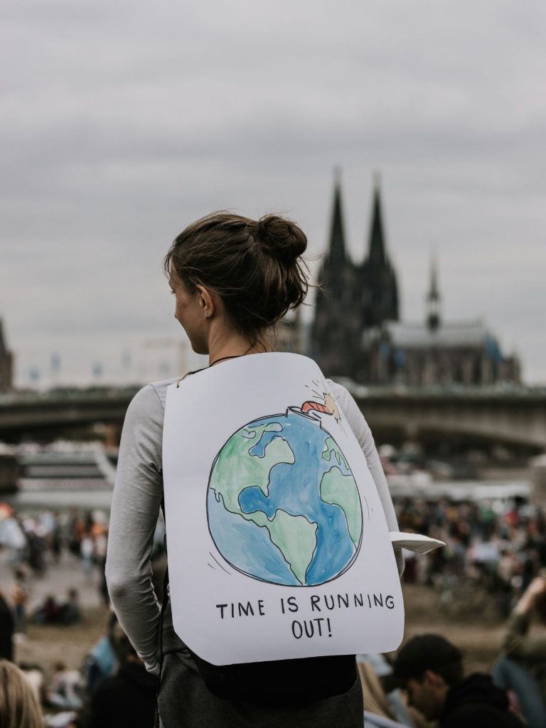 Aktivista a klímaválságra figyelmeztet hátára erősített plakáttal