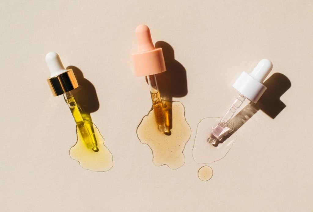 mandulasav-hatoanyag-valasztas | Marie Claire Három féle mandulasavas szérum pipettája, alatta kifolyt szérum, bézs háttér