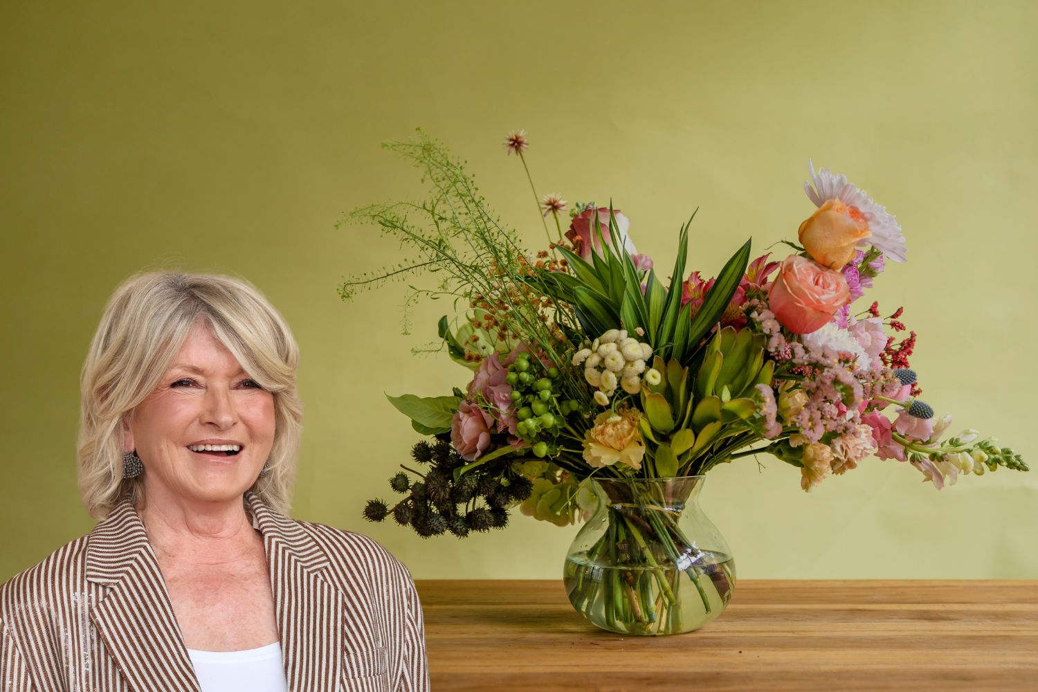 Martha Stewart portré a bal alsó sarokban, háttérkép virágcsokor asztalon, zöld fal