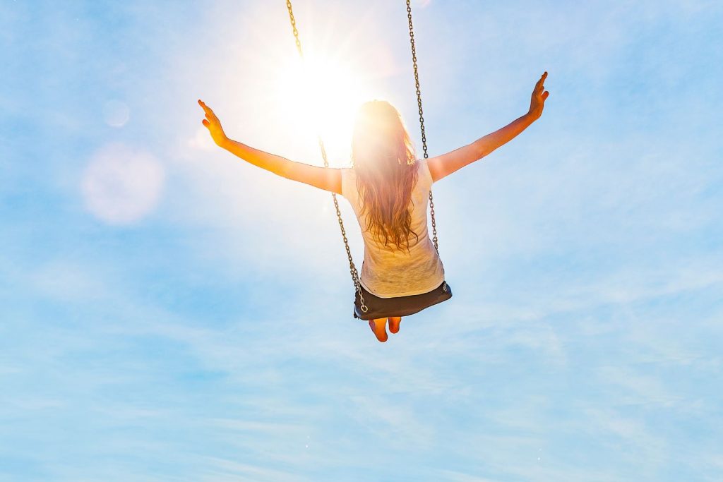 Nő hintán kék égbolt előtt
