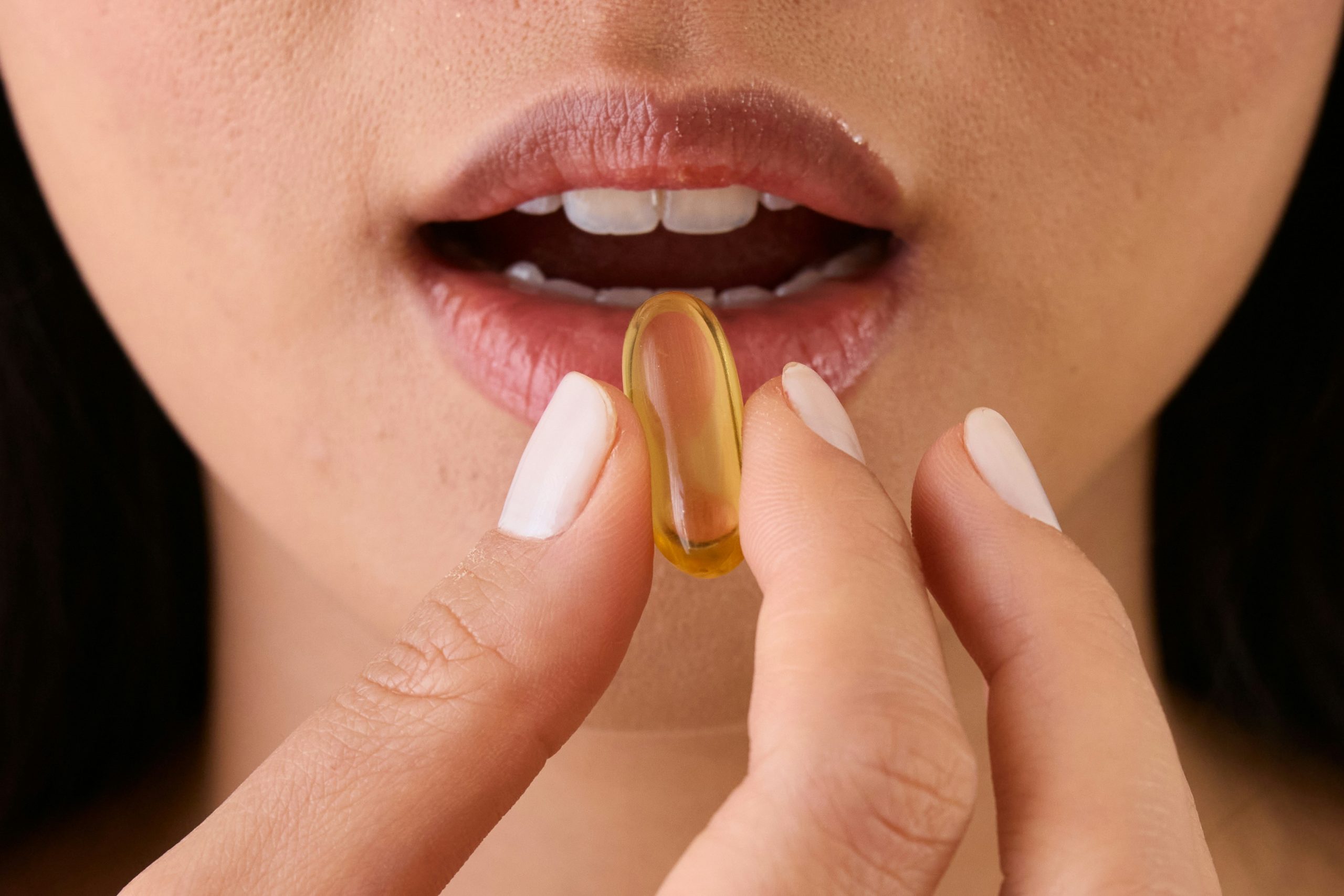 Női kéz vitamint emel a szája elé