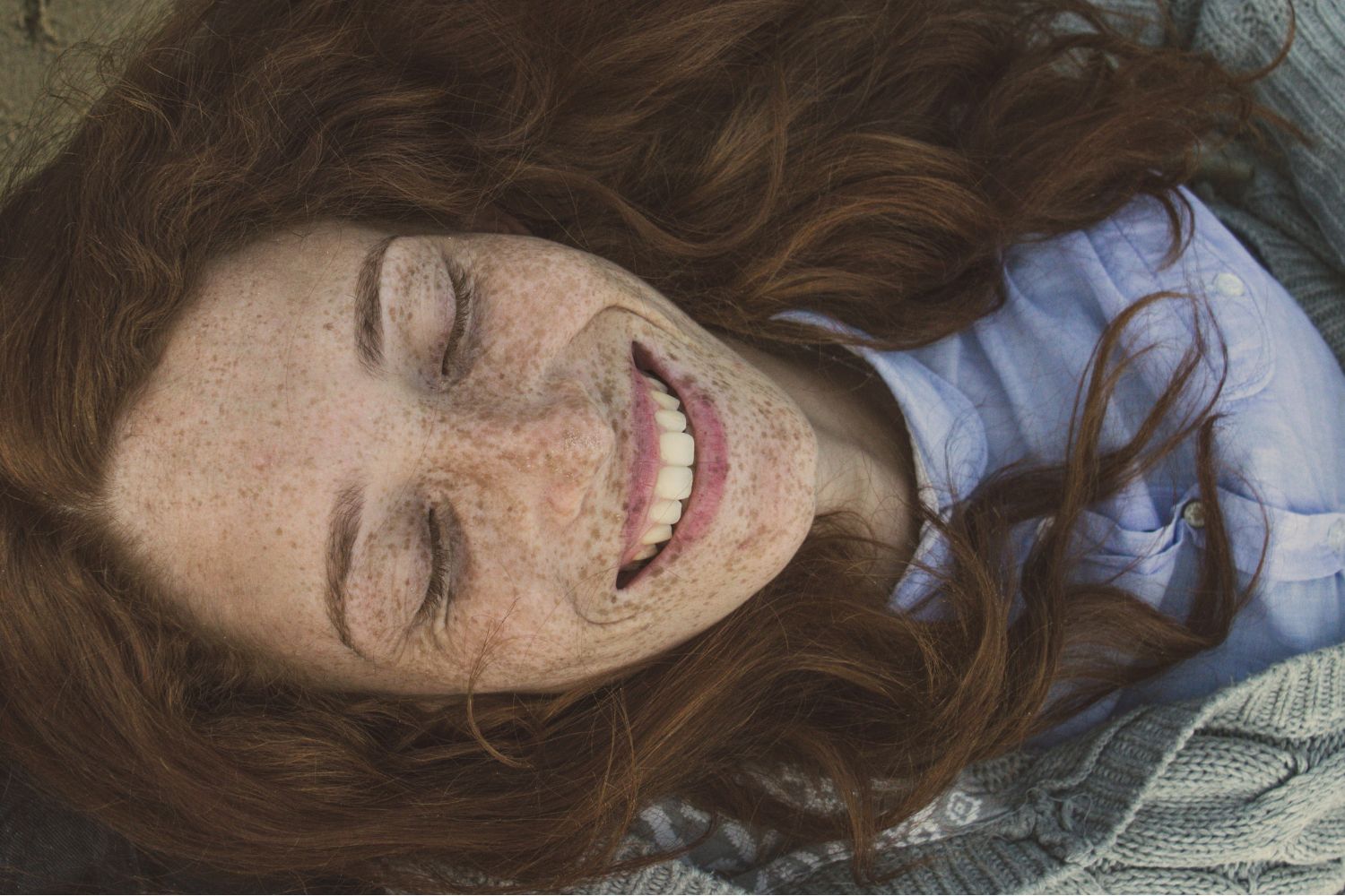 Szép, fiatal szeplős arcú nő nevet álmában közeli portrén