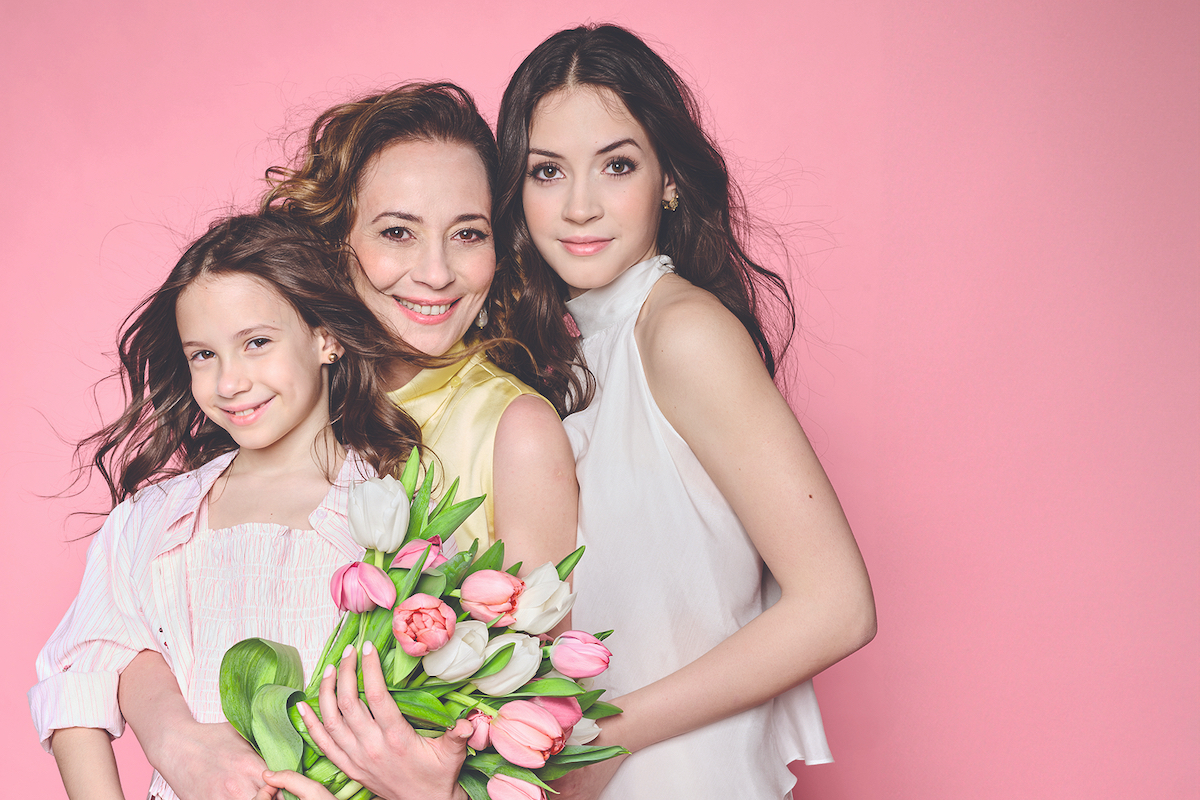 A Nők Lapja friss számának címlapsztárja Farkasházi Réka és lányai, a tizenhét éves Rebeka és a hétéves Tamara rózsaszín háttér előtt, tulipánokkal.