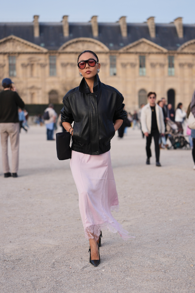 Xiayan Guo sötét fekete haját kontyba fogja, sötét fekete napszemüveget, nagy ezüst fülbevalót, sötét fekete bőrdzsekit, világos rózsaszín áttetsző / csipke szegélyű kombiné ruhát és sötét fekete bőr hegyes orrú pumps magas sarkú cipőt visel