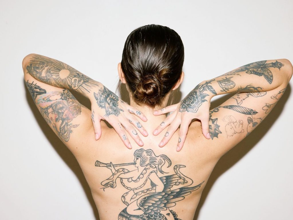 Nő háttal nagyméretű tetoválásokkal a felsőtestén