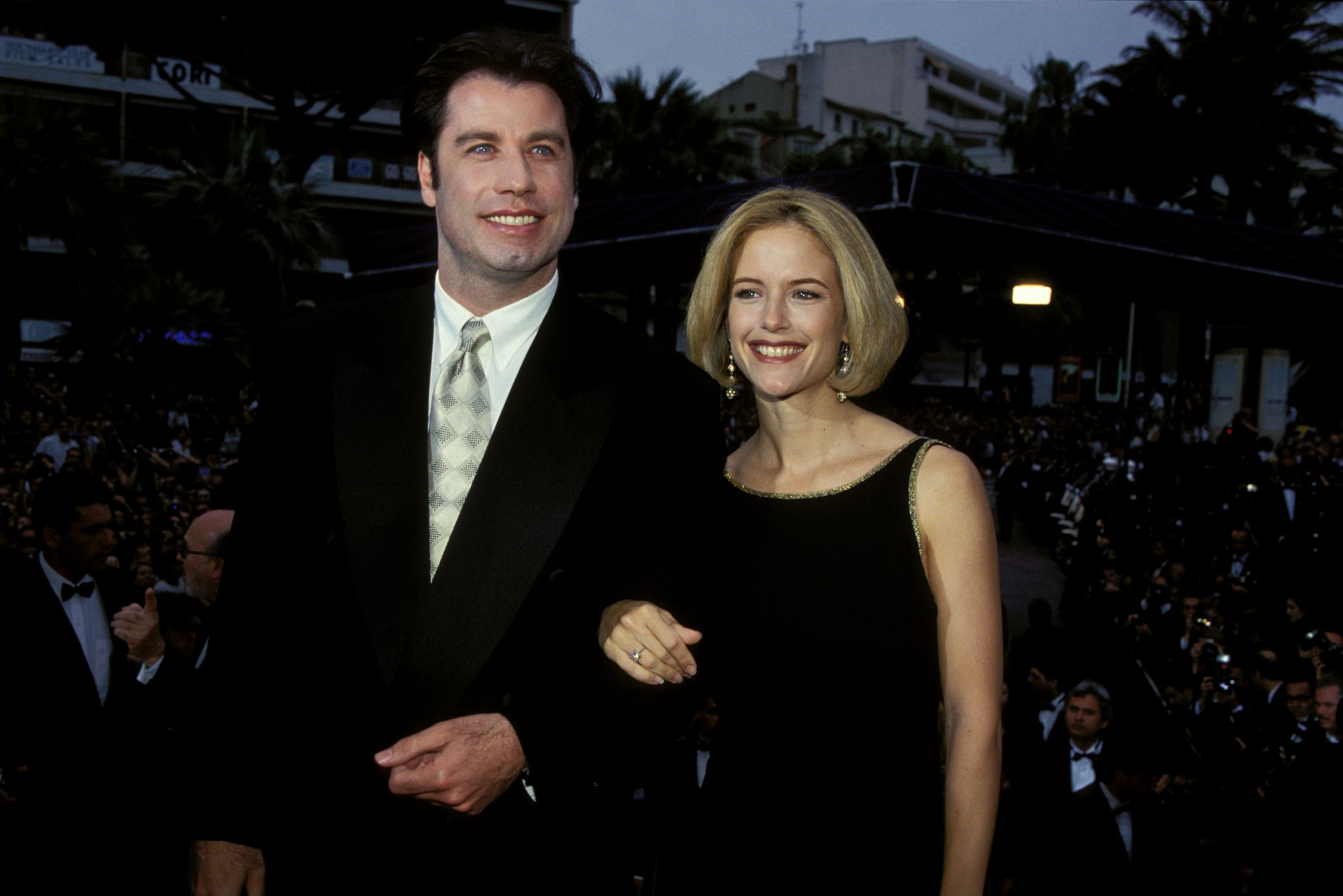 John Travolta öltönyben és felesége, Kely Preston fekete ruhában belekarol, Cannes-ban 1994-ben.