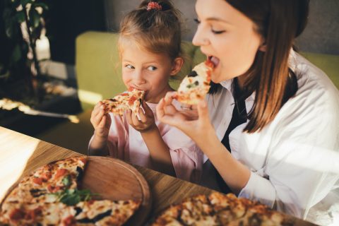 Anyuka és kislánya vidáman pizzát esznek egy étteremben