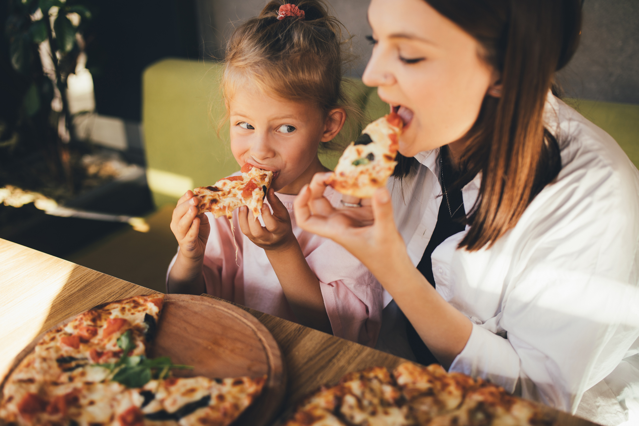 Anyuka és kislánya vidáman pizzát esznek egy étteremben