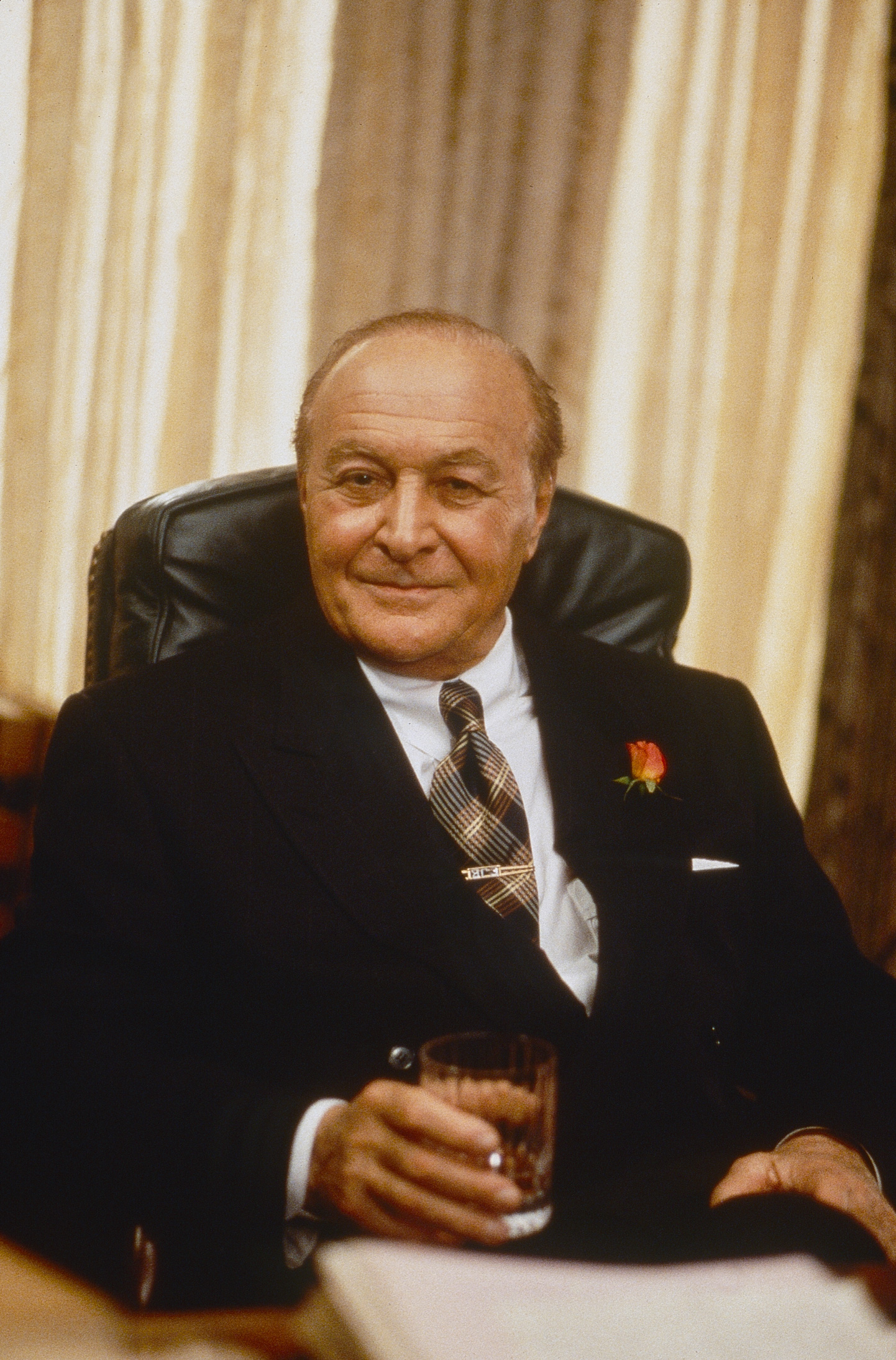 sztarok-70-es-evek-hollywood | Marie Claire Robert Loggia öltönyben, egy italos pohárt fogva a kezében ül egy bőrfotelben.