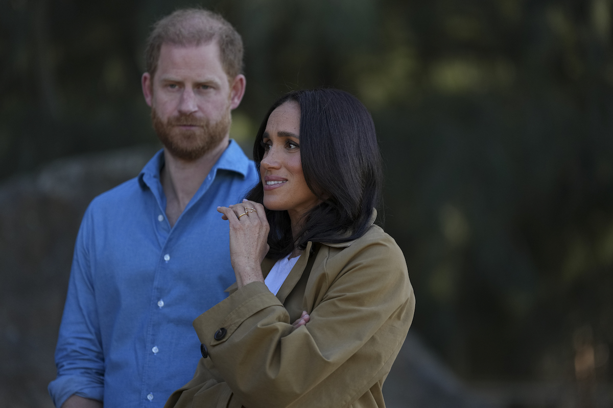Harry herceg kék ingben, mellette Meghan barna trench kabátban