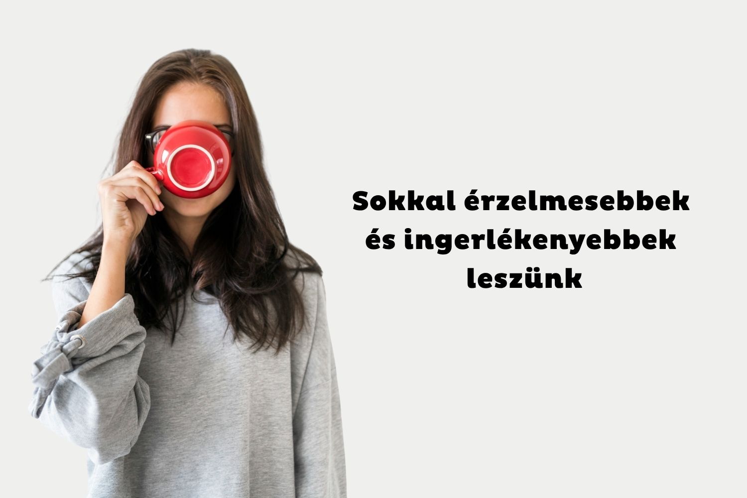 Szürke pulcsis, hosszú, barna hajú nő piros kávéscsészét emel a szájához