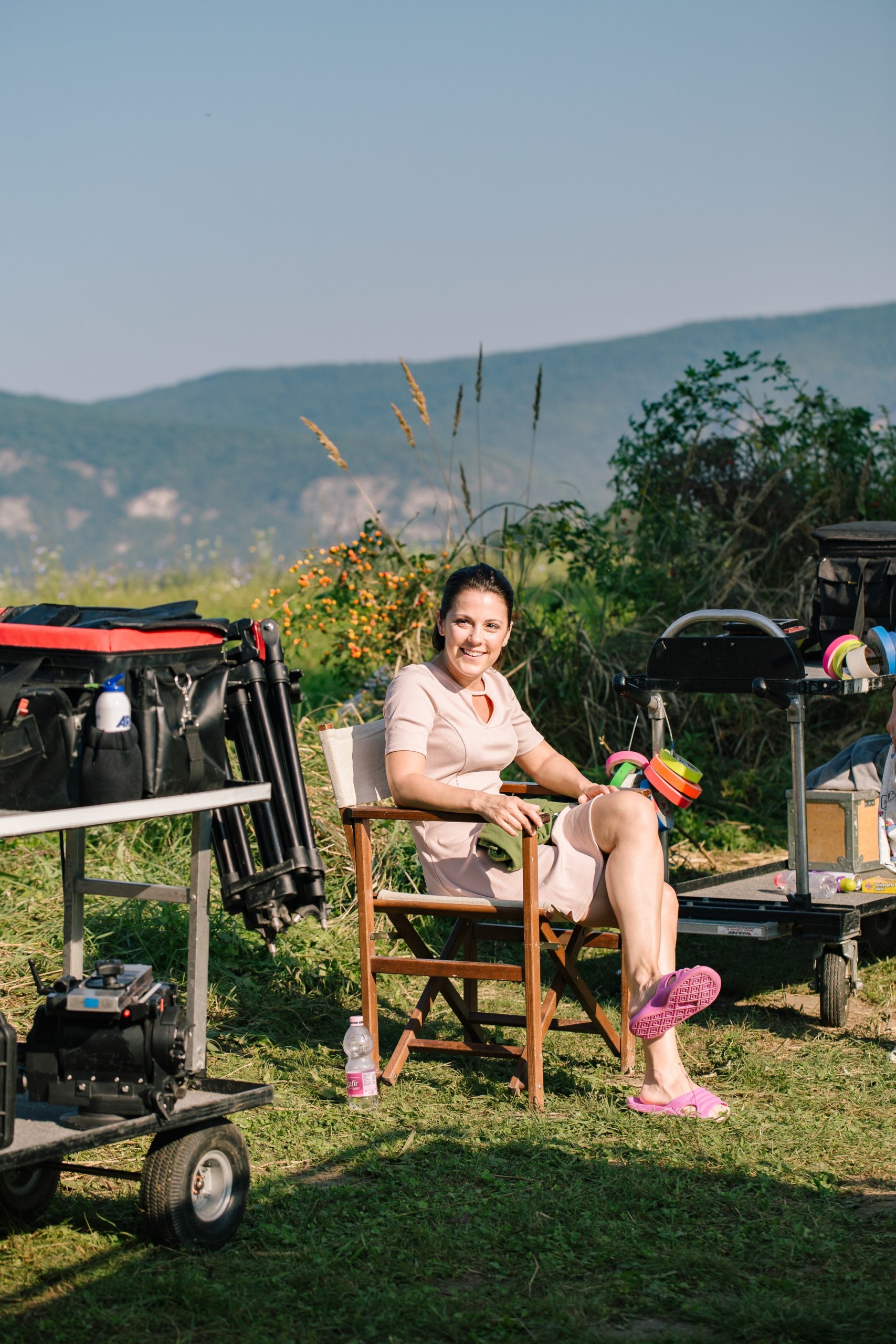 Lovas Rozi az RTL Klub nagysikerű sorozata: A mi kis falunk forgatásán, székben ülve mosolyog, a lábán rózsaszín papucs