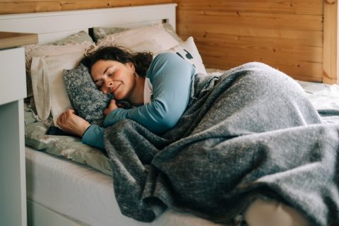 Egy nő boldogan fekszik az ágyában